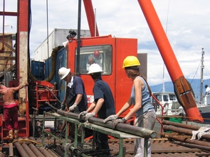 Members of the Lake Malawi Drilling Project science team handle the corer — part of the equipment used to collect sediment cores from the bottom Lake Malawi. Note the sediment in the end of the metal tube. (Photo courtesy of the Lake Malawi Drilling Project) Members of the Lake Malawi Drilling Project science team handle the corer — part of the equipment used to collect sediment cores from the bottom Lake Malawi. Note the sediment in the end of the metal tube. (Photo courtesy of the Lake Malawi Drilling Project)